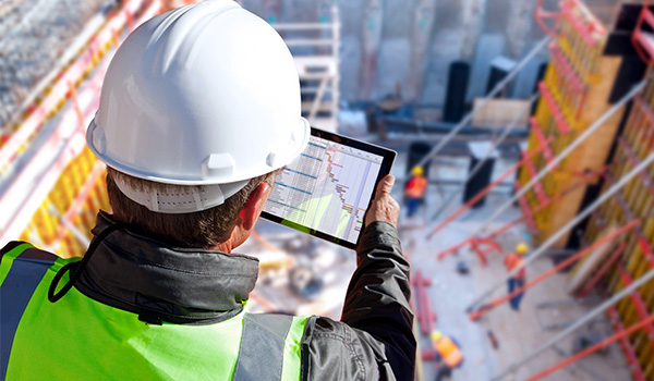 Construction foreman holding tablet above site